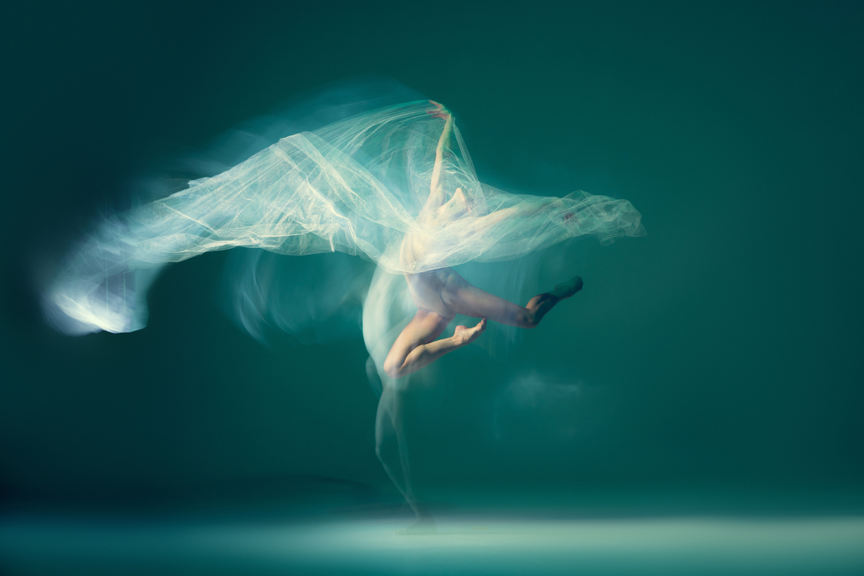 Woman dancing with floating fabric leaping into the air