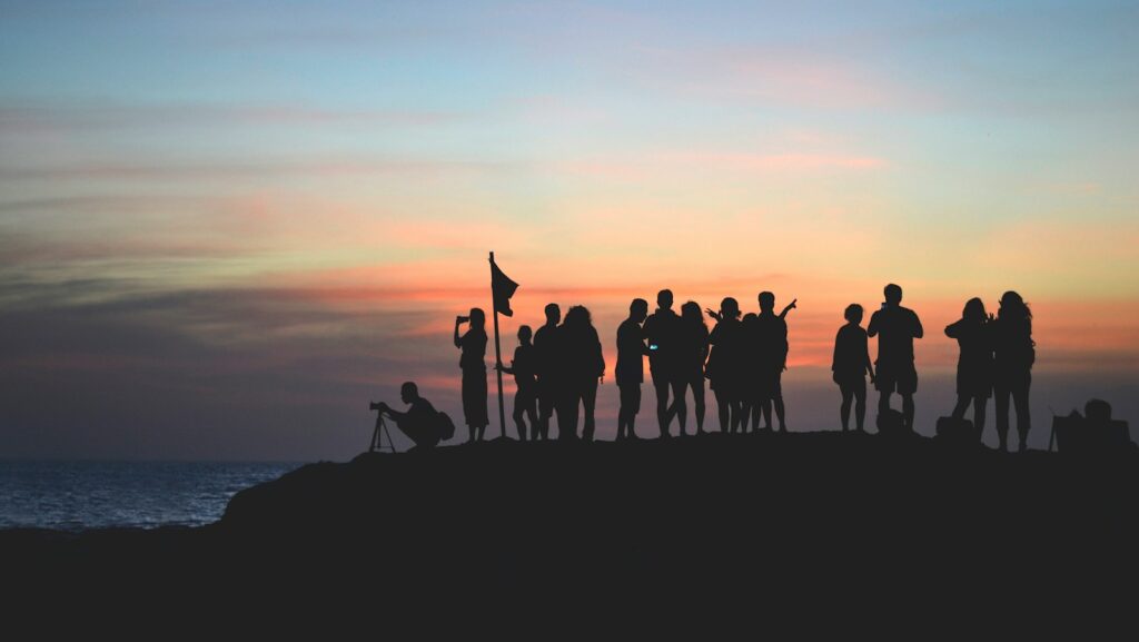 silhouette photography of people gathered together on cliff