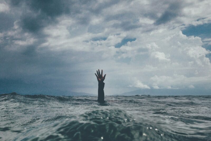 photo of person reach out above the water representing stress