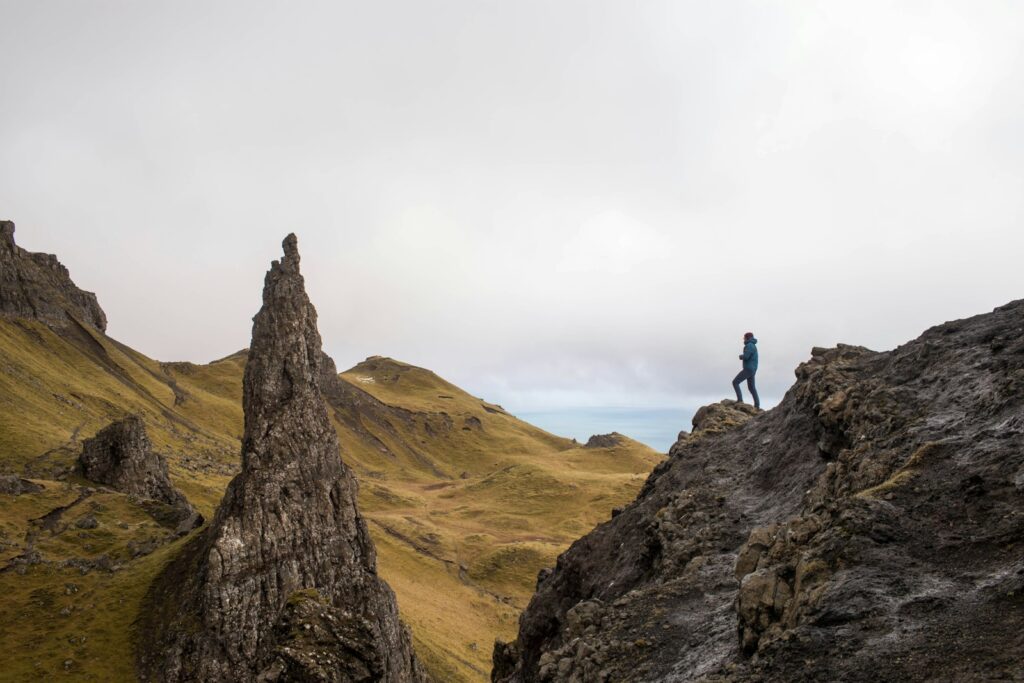 person standing on top of rock formation symbolising overcoming challenges