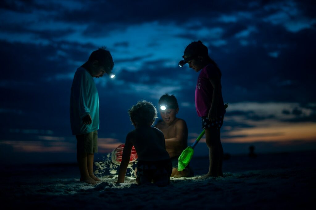 child in black jacket and blue shorts holding green plastic bucket - childhood leadership