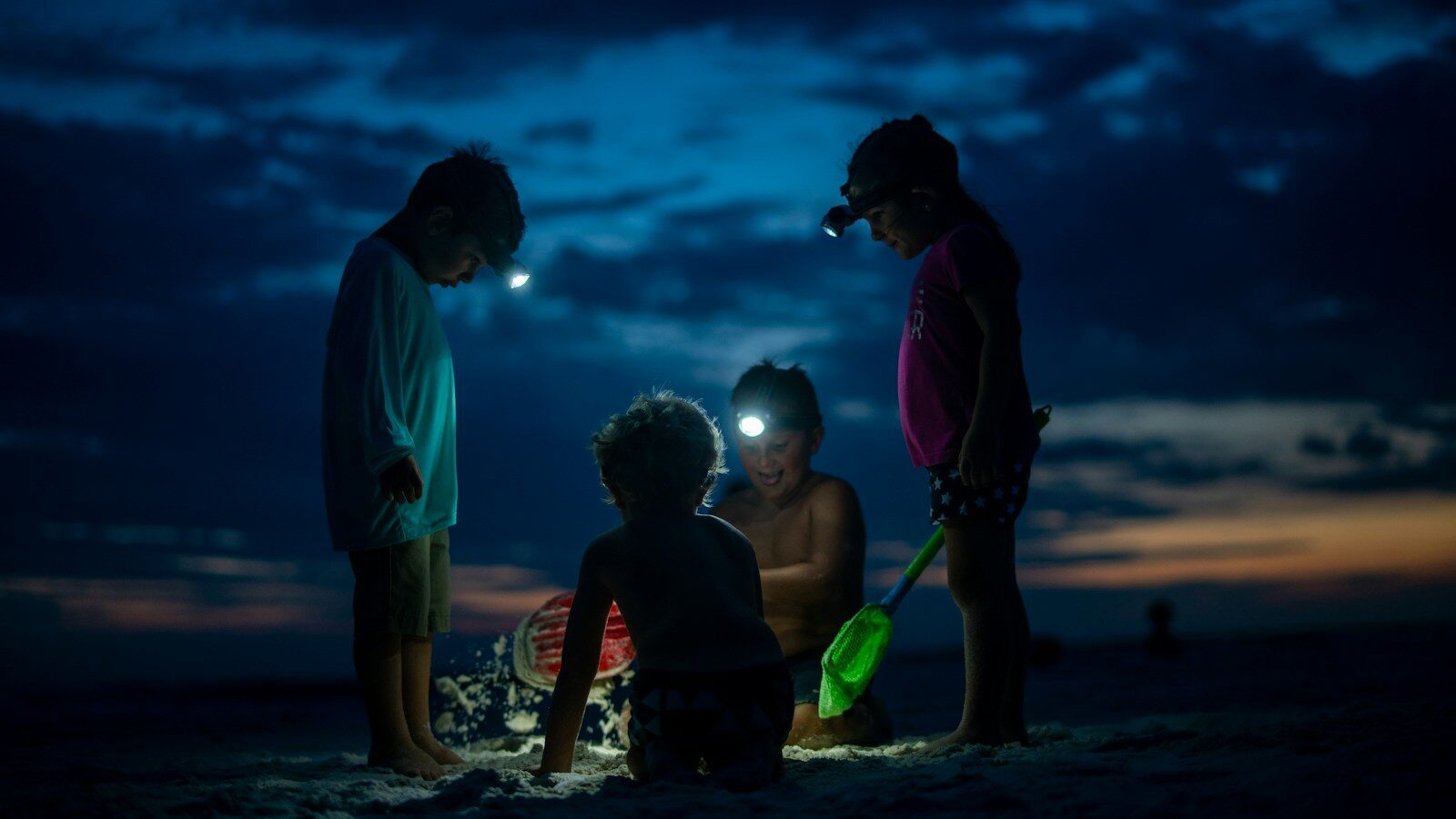 child in black jacket and blue shorts holding green plastic bucket - childhood leadership