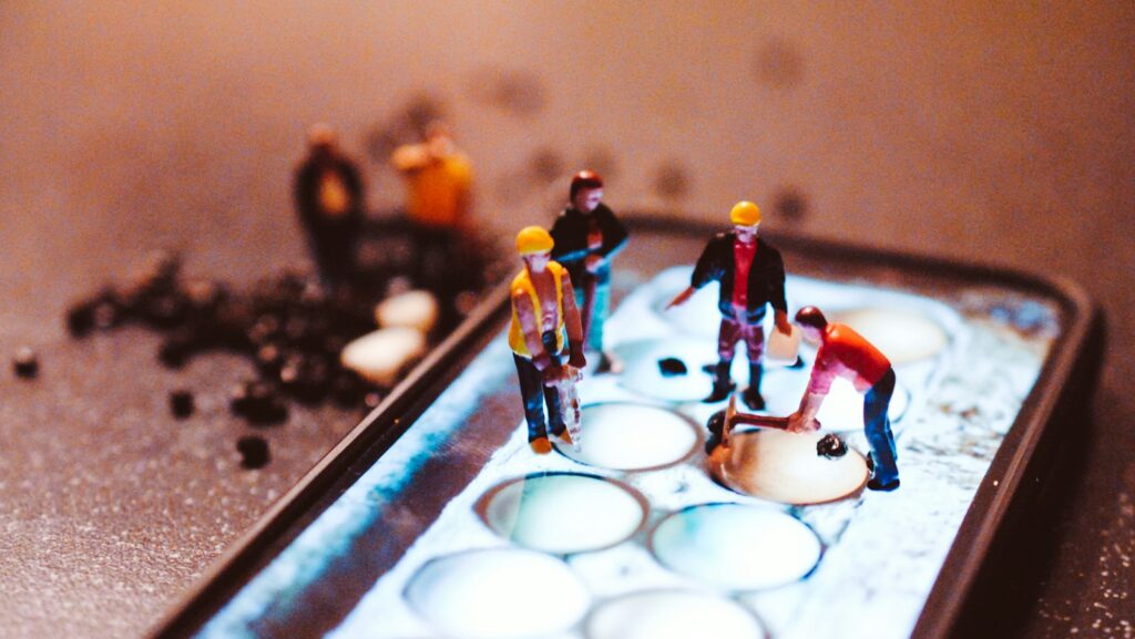 tiny model construction workers, working on a mobile phone screen: skills depiction