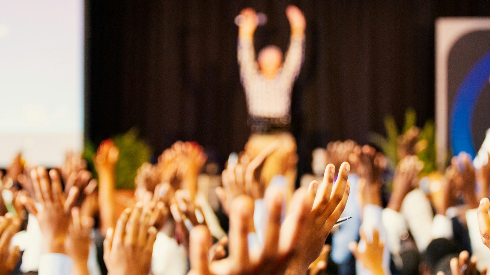 people raising hands with bokeh lights, Autumn conference season.