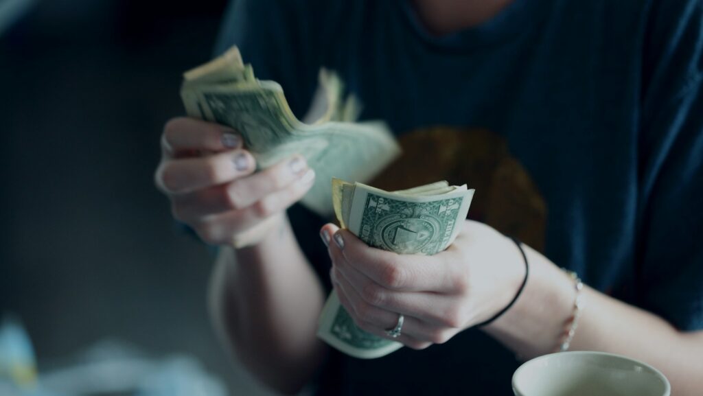 focus photography of person counting dollar banknotes. Wasting money on AI