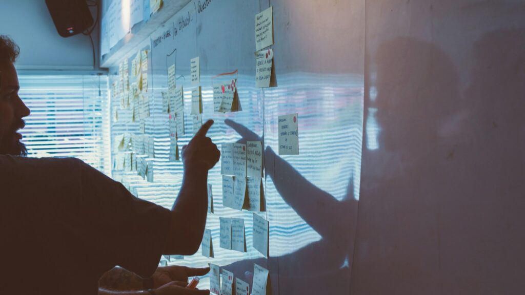 person pointing white paper on wall