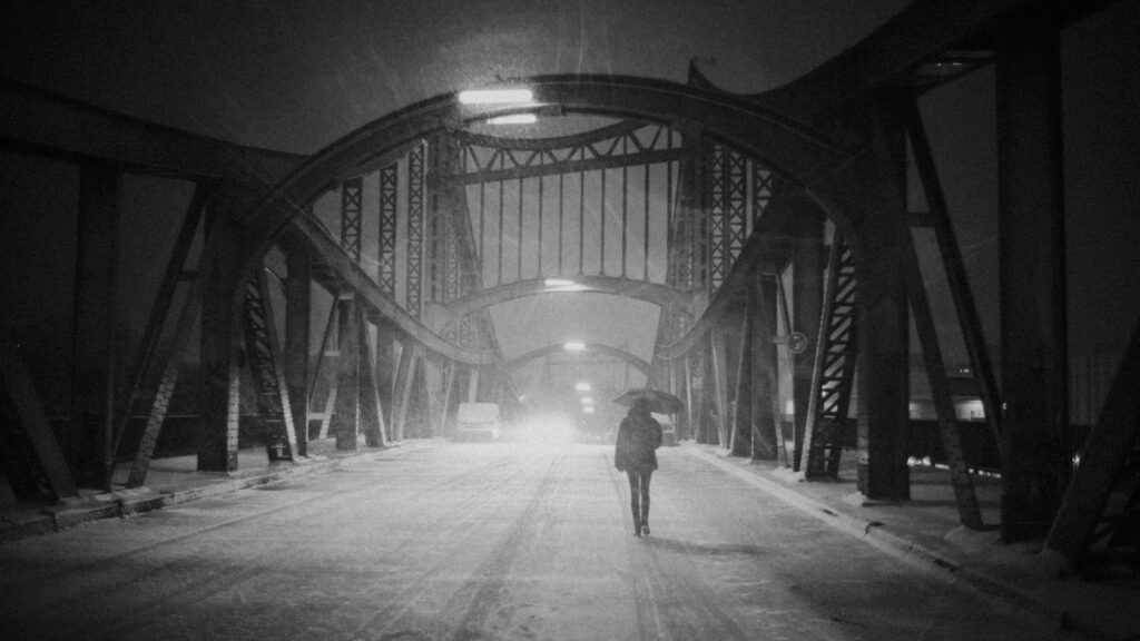 grayscale photo of woman under umbrella walking on suspension bridge, learning transfer