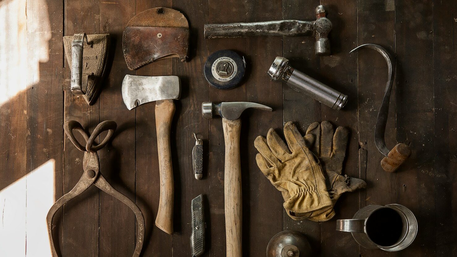 tools for leaders who coach, clothes iron, hammer, axe, flashlight and pitcher on brown wooden table