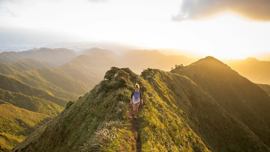 woman walking on pathway on top of hill at golden hour