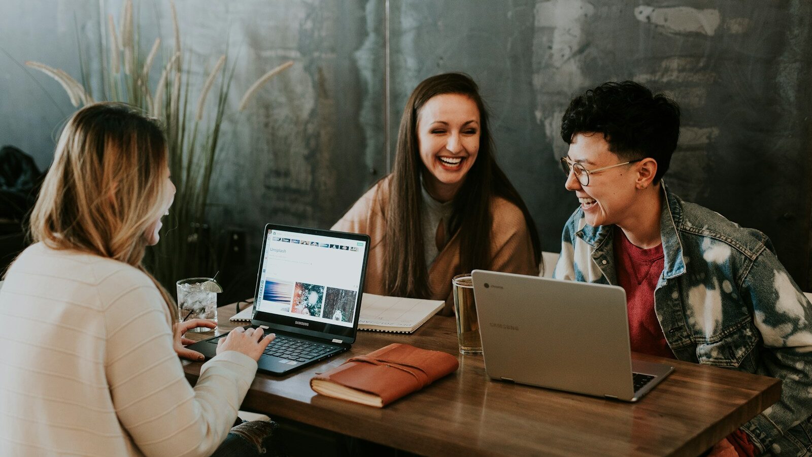 three people sitting in front of table laughing together