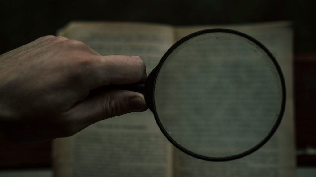 person holding magnifying glass with black frame