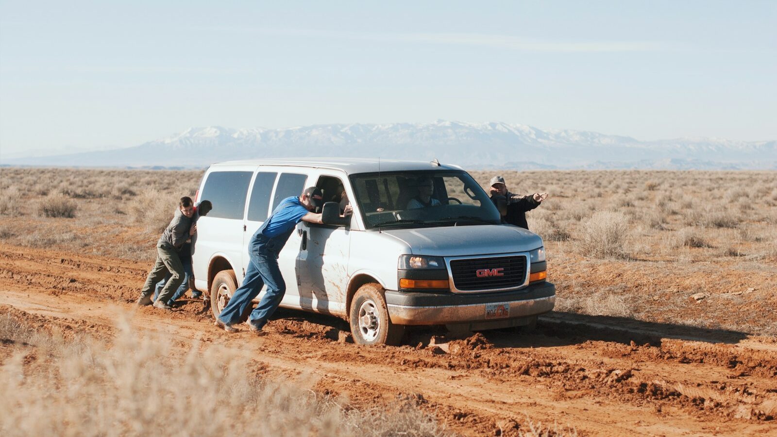 men pushing white GMC van, depicting stuck team and lack of leadership development