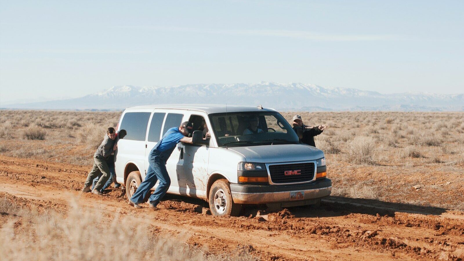 men pushing white GMC van